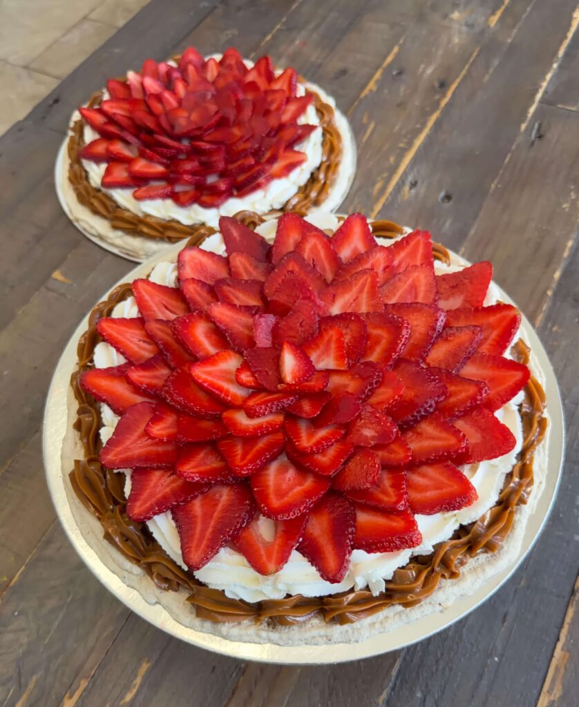 Strawberry and dulce de leche Pavlova dessert tart topped with layered fresh strawberries and whipped cream.