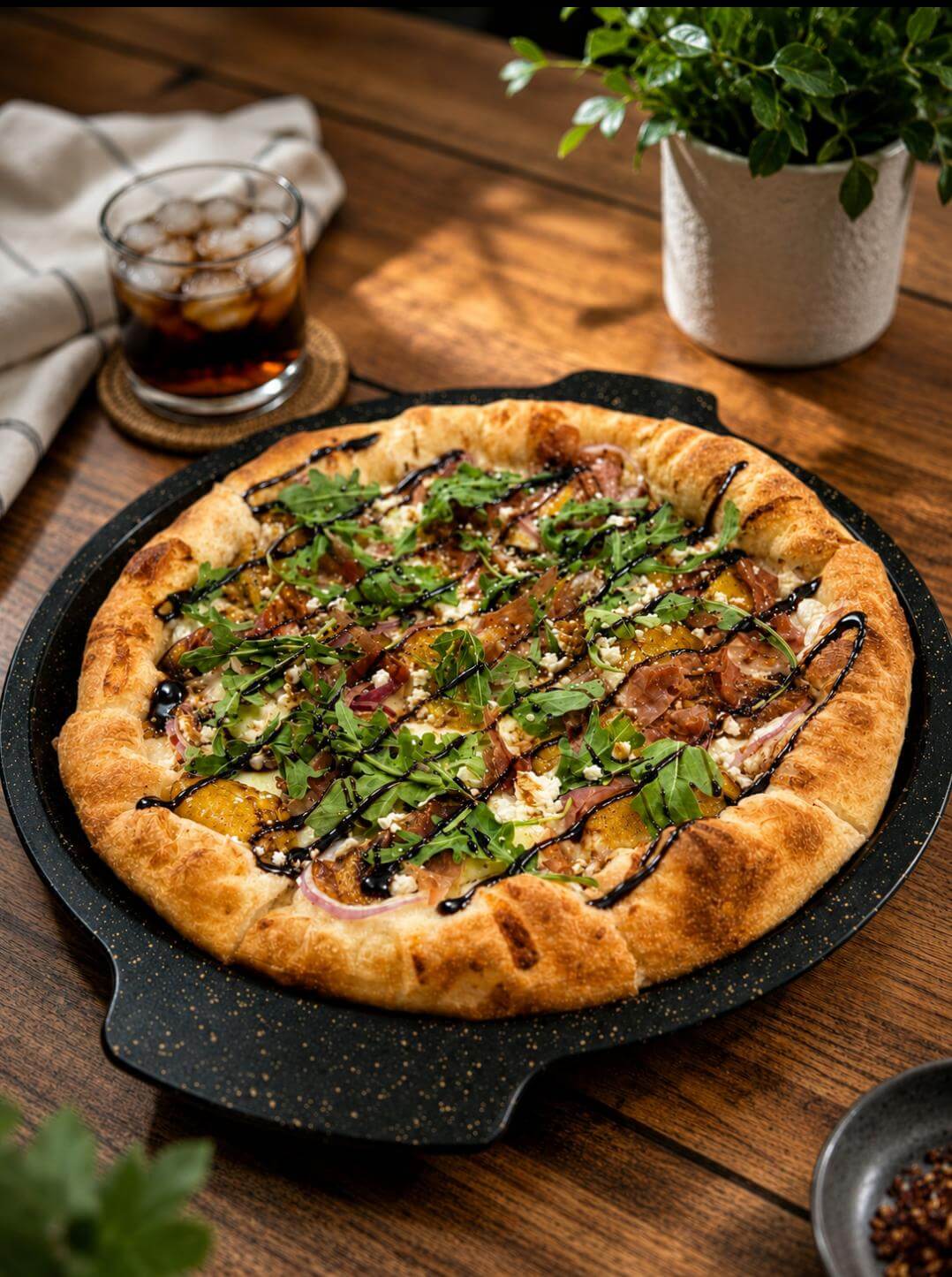 Artisan pizza with prosciutto, roasted peaches, arugula, goat cheese, red onions, and balsamic glaze on a handcrafted 48-hour fermented crust from Vinny's 48.