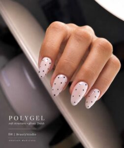 Polygel manicure with a glossy soft pink finish and delicate black polka dot nail art by DR Beauty Studio.