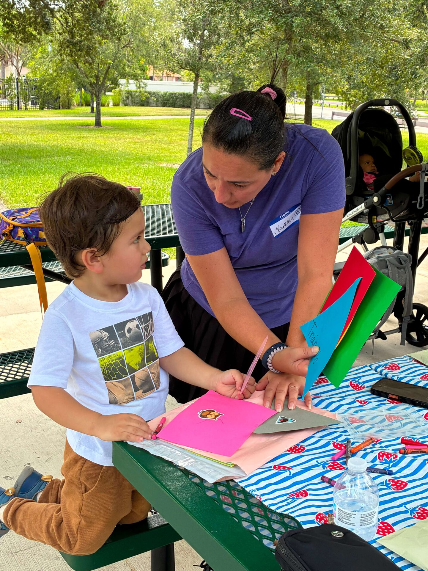 Language therapist guiding young children during a colorful hands-on painting activity outdoors, encouraging learning through play and creativity.