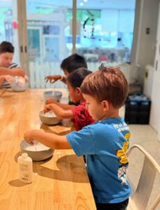 Student exploring a colorful hands-on science experiment during a bilingual English-Spanish Future Minds Little Scientist STEAM class.