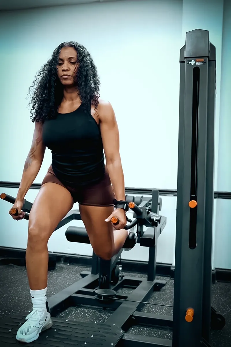 Woman performing a lower-body strength exercise on a weight machine at University Fitness Center.